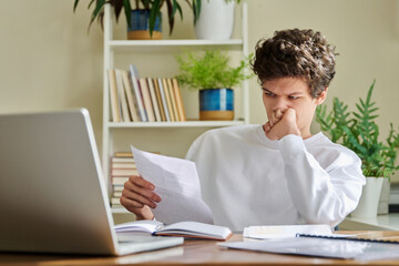 Serious young guy reading letter, paper document