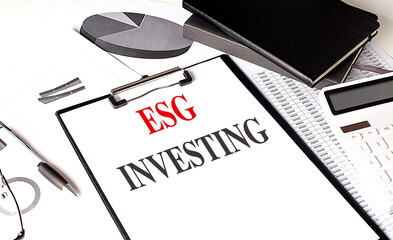 ESG INVESTING text on clipboard on chart with notebook and calculator