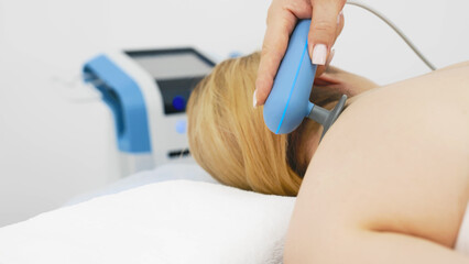 Young woman receiving electromagnetic therapy in a modern clinic. The treatment speeds up tissue...