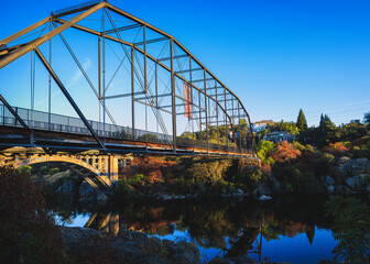Fototapeta premium American flag hangs on the truss bridge in Folsom California at sun down with sharp reflection's 