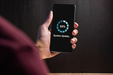 Hand holding a smartphone with software system or application update process on screen