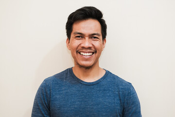 Portrait of happy Southeast Asian man in long blue sleeve on isolated white background, positive emotion, copy space.