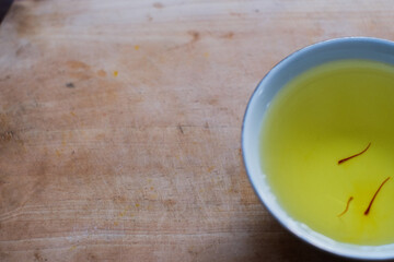 A saffron water mix in white cup in wooden cutting board, herbal tea, healthy drinks.