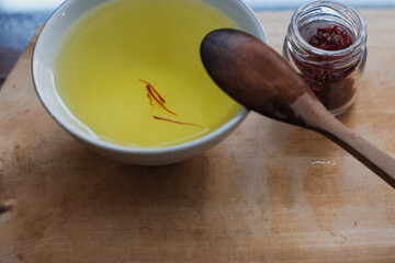Pile of dried saffron at glasses jar And saffron water mix white cup and wooden spoon in wooden cutting board, herbal tea, healthy drinks.