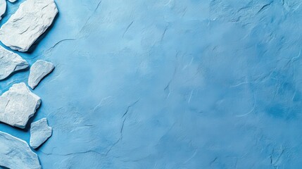 Naklejka premium A textured blue surface with scattered white stones, creating a serene backdrop ideal for various creative projects.
