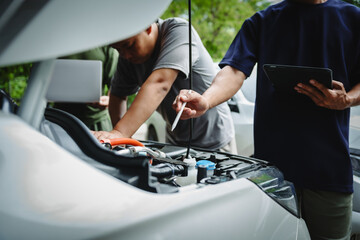 Three Asian men discussing car insurance policies with adjuster. They review details such as...