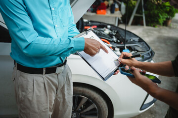 Car seller agent signs a car insurance agreement with salesman. The document outlines vehicle policy, premium, rental terms, with contract paper finalized using car insurance claim mobile phone.