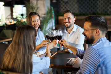 Group of happy business colleagues toasting with wine in a restaurant