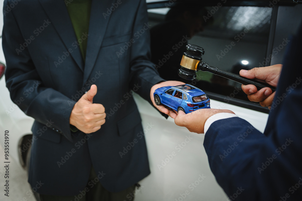 Wall mural Two Asian individuals discuss a car insurance claim with an agent in front of a damaged vehicle. They review documents, discuss the policy, and address the crash and repair costs.