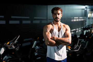 Portrait of caucasian muscular sport man with perfect abs and bicep muscle inside gym with dark background for exercising and workout in high contrast low key lighting studio