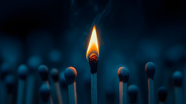 Single lit match among unlit matches, deep blue color tone, dramatic lighting, shallow depth of field, dark moody atmosphere, contrast of warm flame and cool background.