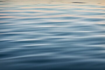 A calm ocean surface with gentle ripples reflecting the morning sky, Ai generated