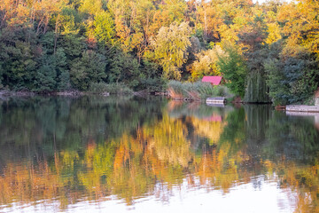 Colorful autumn trees and wooden house reflection in the water