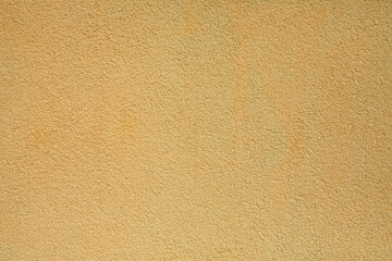 Yellow or dark-yellow wall, texture, background. Decor of contrasting yellowed textured coating. Structural plaster, rough, uneven surface in yellowish color. Modern exterior cladding of buildings