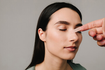 Rhinoplasty. Plastic surgeon is taping nose to patient during rhinoplasty recovery. Applying...
