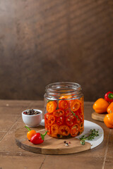 Fermented preserved vegetarian food concept. Mini colorful bell pepper glass jars over rustic kitchen table. Canned food concept.