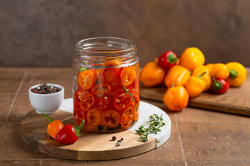 Probiotic foods. Eco friendly still life with pickled or fermented vegetables. Mini colorful bell pepper in glass jars on rustic wooden background . Home food preserving or canning