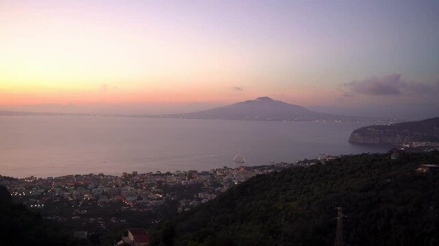 Day to Night Timelapse of dramatic clouds moving over Sorrento city against mediterranean sea and mt vesuvius volcano during sunset , campania region Italy, Europe