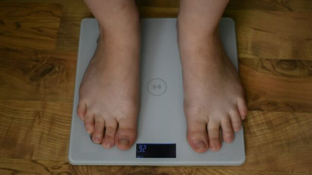 Woman's feet on scales. A woman steps on the scale barefoot. Scales on light parquet. Concept of weight loss and overweight in people. Good and correct weight for people. measuring weight, close-up.