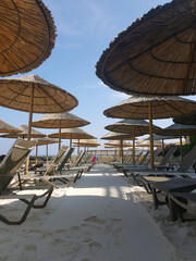 empty beach with sun loungers and straw umbrellas on the sand
