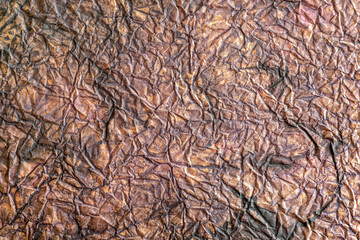 Crumpled chaotically colored brown paper as a background.
