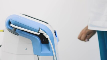 A healthcare professional activates advanced electro-wave therapy equipment in a state-of-the-art clinic. This modern treatment aids in pain relief and muscle recovery, promoting overall health 