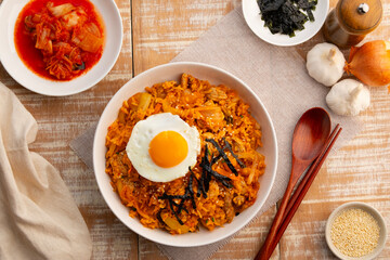 Kimchi fried rice with pork topped with fried egg sesame seed and Crispy Seaweed in white plate.Korean food.Top view.