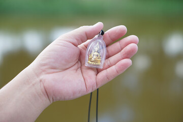 Hand holds Buddha amulet. Concept, faith and belief of Buddhist for holy to protect from dangers, bring good luck, business prosperity and wealth. Collecting amulet as hobbies, exchange, sell or buy. 