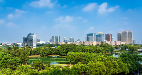 Obraz premium Scenic Urban Skyline Surrounded by Lush Greenery and Blue Skies