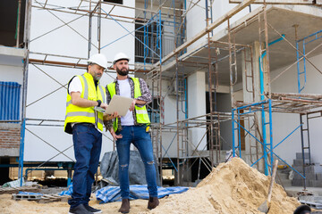 Architect and contractor working on building in construction site. Two Professional Architects Engineer Working on Personal laptop computer at house construction site