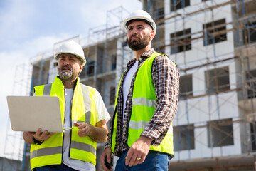 Architect and contractor working on building in construction site. Two Professional Architects Engineer Working on Personal laptop computer at house construction site