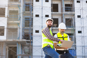 Architect and contractor working on building in construction site. Two Professional Architects Engineer Working on Personal laptop computer at house construction site