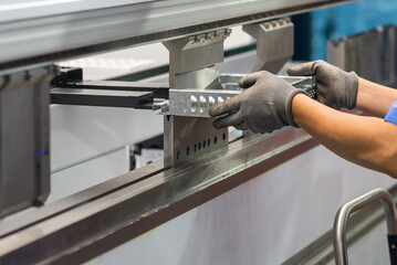 Close up the hydraulic press brake bending machine operator hold the sheet metal parts with safety...
