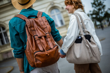 Ginger girlfriend and her boyfriend holding hands while exploring the new city and looking at the monuments and buildings on their vacation.