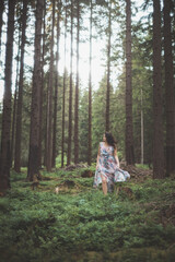 Pretty young brunette aged 20-25 is running around the forest in a colourful dress. Joy of clean air and the power of nature. Forest fairy