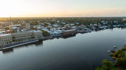 Obraz premium Aerial view of historic downtown Wilmington, NC, with buildings reflecting the sunrise over the Cape Fear River.