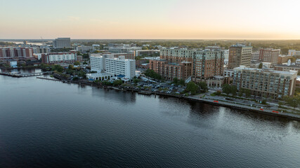 Fototapeta premium Aerial view of historic downtown Wilmington, NC, with buildings reflecting the sunrise over the Cape Fear River.