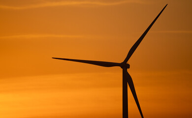 Wind turbine silhouette against sunset sky. Wind power. Sustainable renewable energy generation. Green technology for eco-friendly power production and environmental conservation. Natural landscape.