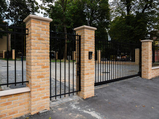 black metal fence with gate and yellow facing brick