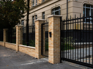 black metal fence with gate and yellow facing brick