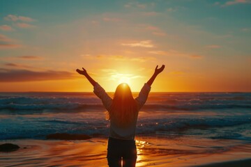 Happy woman at sunrise on beach with arms raised.
