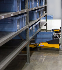 Autonomous robot picking materials from multi-layer rack in modern industrial warehouse.