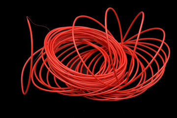 Red fishing line for a brush cutter with rings on a black background.