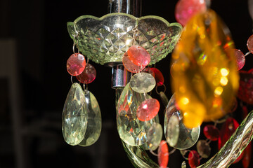 Detail of a brightly green colored retro style chandelier in the interior of a house. It is made of multicolored crystals of different shapes imitating cut crystal jewelry. interior decoration