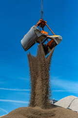 Grab crane fills sand on a hill