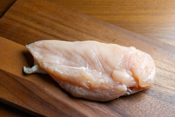 木製のカッティングボードの上の鶏むね肉