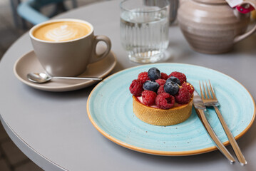 Dessert tartlet with berries on tables in a sidewalk cafe.