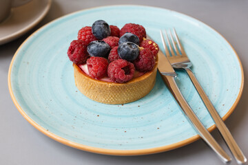 Dessert tartlet with berries on tables in a sidewalk cafe.