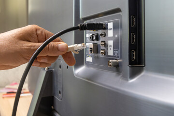 Man connects internet cable to the TV.