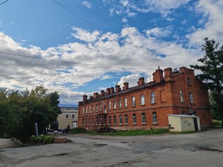A large brick building with a lot of windows sits in front of a tree